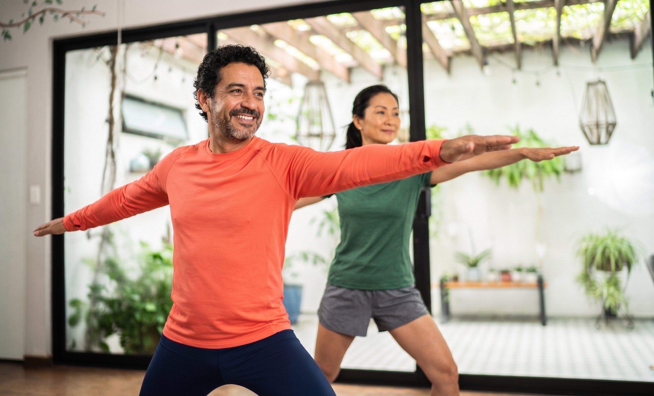 Two adults stretching together in a bright exercise space